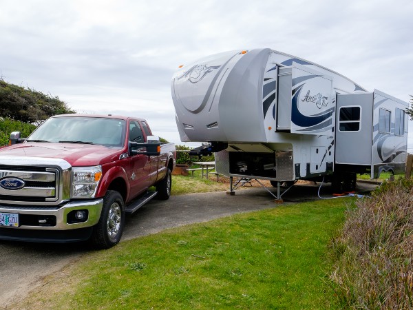 A red Ford truck next to a white fifth wheel