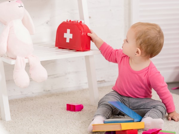 a kid with a first aid kit on a chair behind her