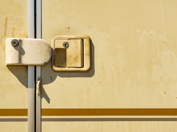 A RV locked door on a dirty white RV