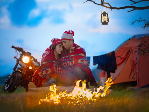 A couple motorcycle-camping sharing a moment near a romantic fire