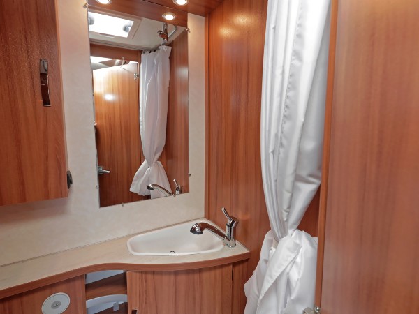 A camper bathroom with a white shower curtain