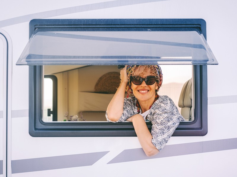 A person looking out the window of a camper