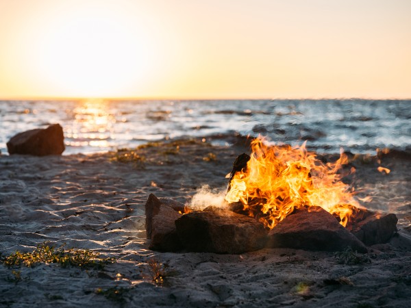 A campfire on a sandy beach close to sunset