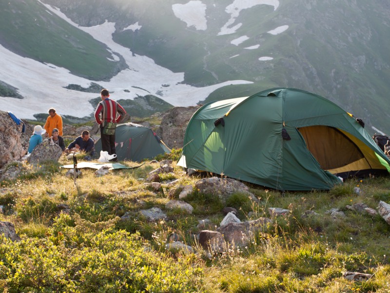 A family camping up in the mountains with a green tent