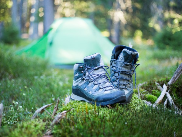 A pair of camping shoes right outside of a green tent