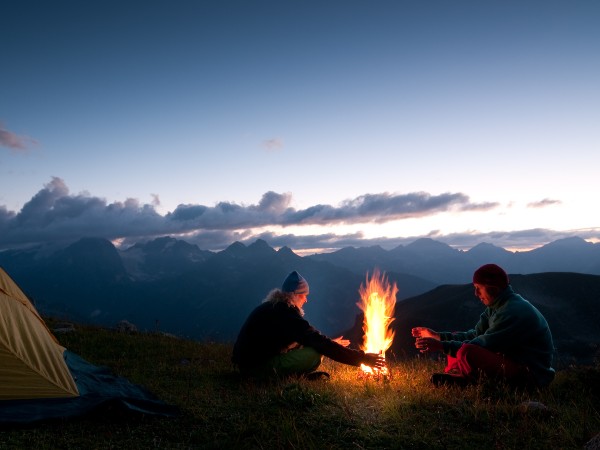 A couple camping in the mountains with a fire going