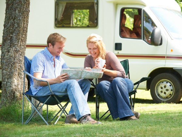 a couple relaxing outside their camper and reading