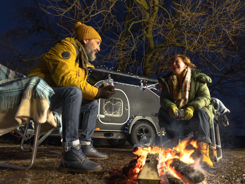 Couple sitting by a campfire on a cold night