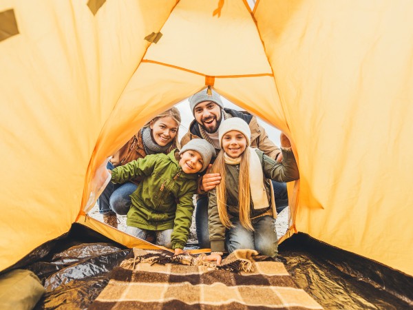 A family looking at a camping cot in the yellow tent