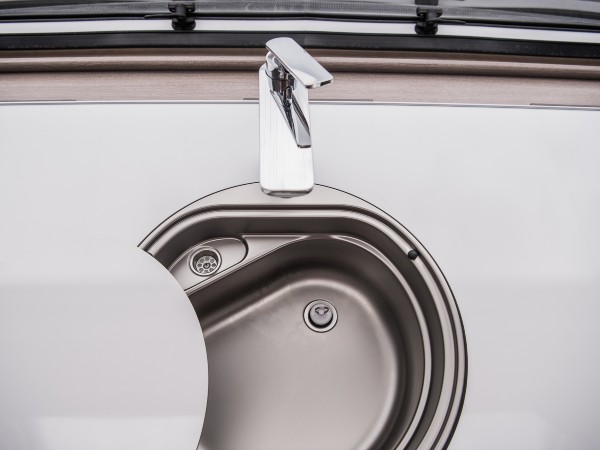 A motorhome kitchen sink with a white countertop