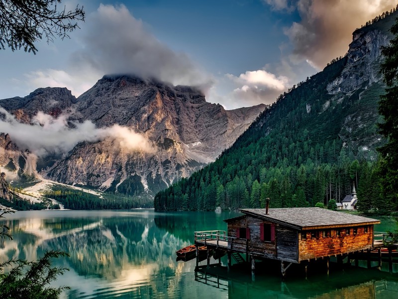 Home overlooking a lake, trees, and a beautiful cloud-covered mountain