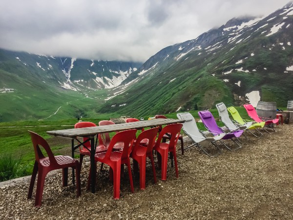 A camping table in the mountains with red chairs surrounding it