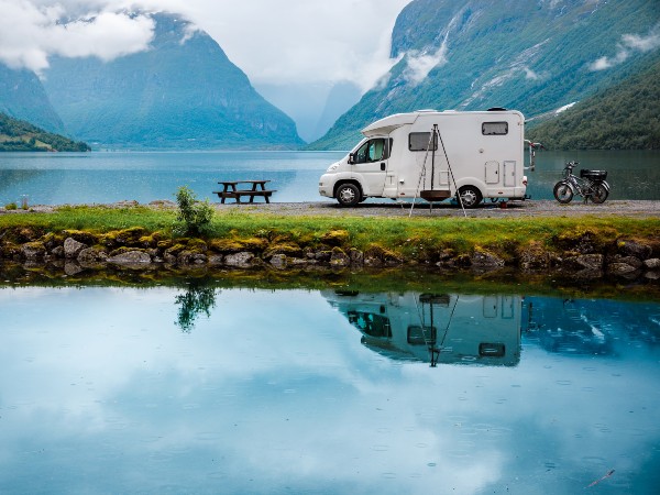 An rv parked right by the lake near the mountains