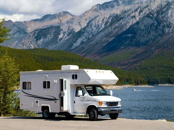 A white rv parked near a lake and the mountains