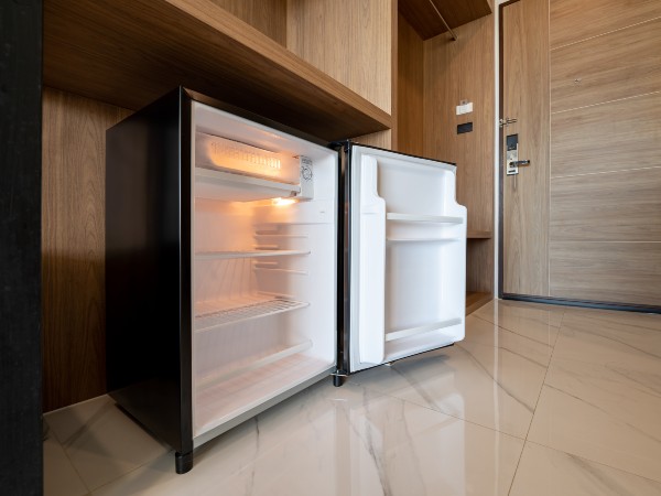 A small RV refrigerator with the door open in the bedroom 