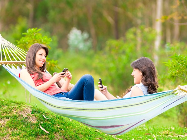 Two girls on a hammock hanging between trees