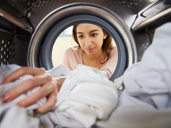 A woman doing laundry and looking in the washing machine