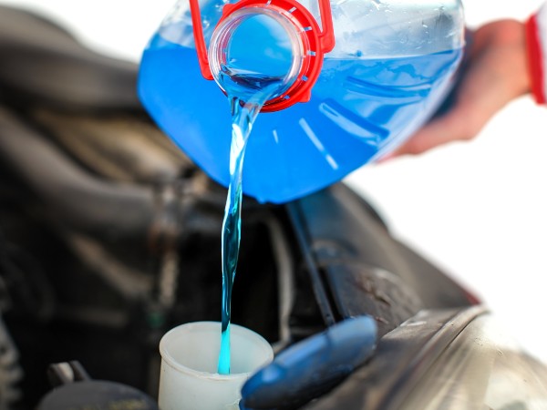 A woman pouring antifreeze into an engine