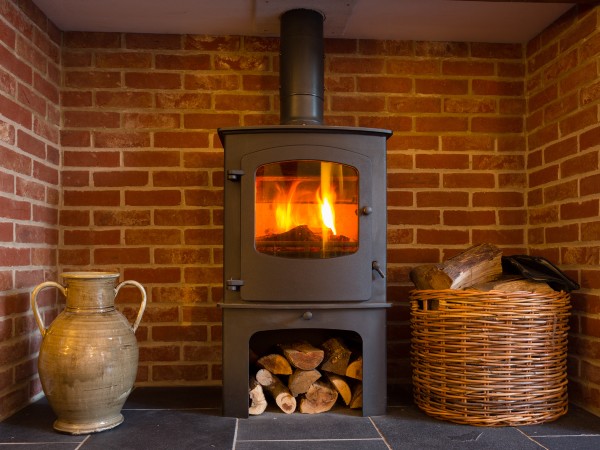 A wood burning stove right by a red brick wall